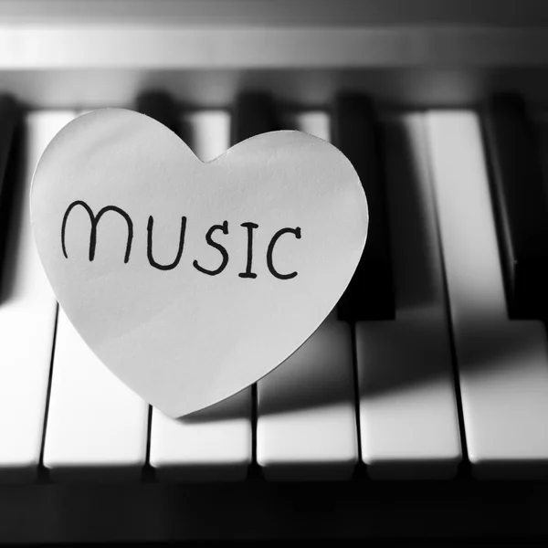 Papper hjärtat på piano keyboard svart och vitt — Stockfoto