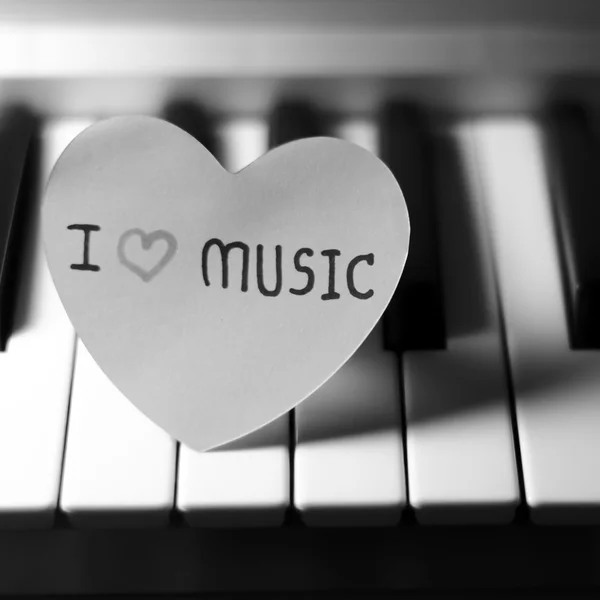 Corazón de papel en el teclado de piano blanco y negro — Foto de Stock