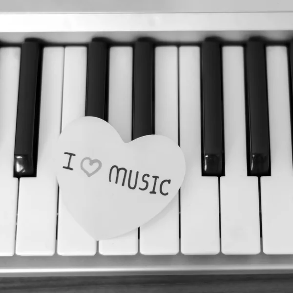 Corazón de papel en el teclado de piano blanco y negro — Foto de Stock