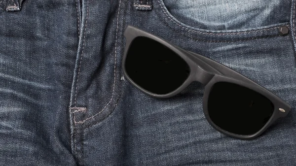 Sunglasses on jean pants — Stock Photo, Image