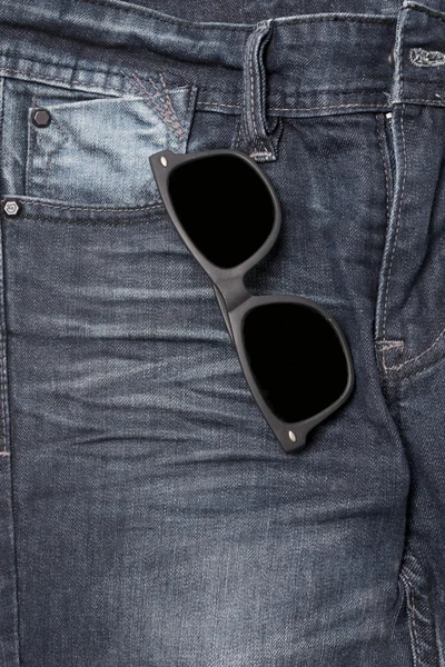 Сонцезахисні окуляри на джинсових штанях — стокове фото