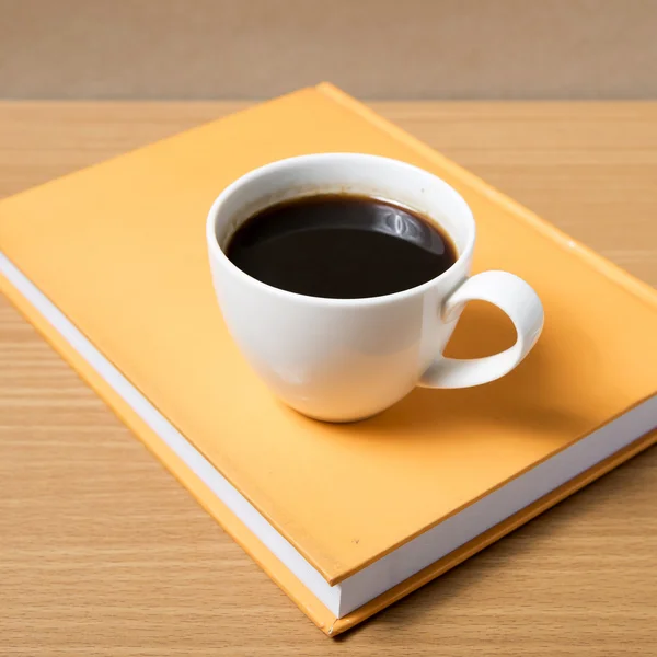 Kaffekopp på orange bok — Stockfoto