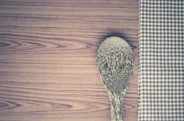 Kitchen towel with spoon on wood background — Stock Photo, Image