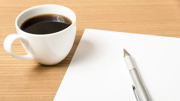 Koffiekopje met wit papier en pen Stockfoto