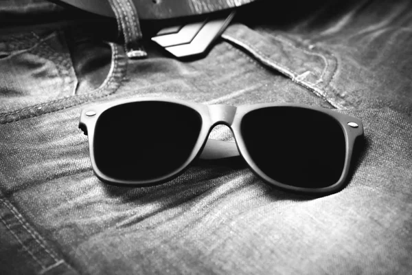 Солнцезащитные очки на джинсовых брюках черно-белый цвет — стоковое фото