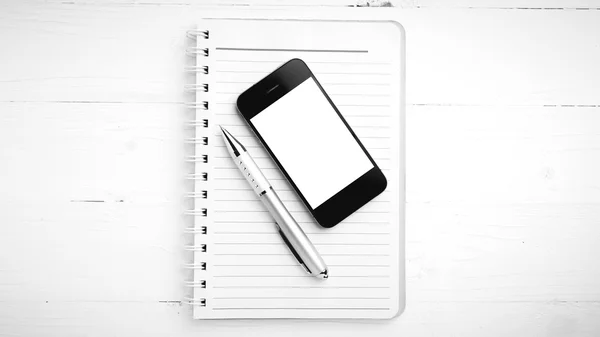 Блокнот и сотовый телефон черно-белый тон стиль — стоковое фото