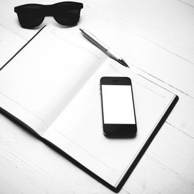 cep telefonu ile defter ve güneş gözlüğü siyah ve beyaz renk arpacık
