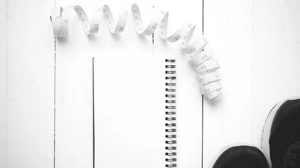 Tênis de corrida com notebook e fita métrica preto e branco t — Fotografia de Stock