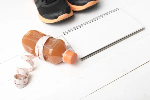 Tênis de corrida, suco de laranja, fita métrica e bloco de notas — Fotografia de Stock