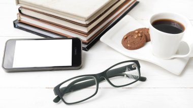 tanımlama bilgisi, telefon, kitap ve gözlük yığını ile kahve fincanı