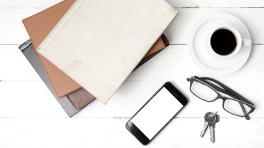 kahve fincanı ile telefon, anahtar, gözlük ve kitap yığını