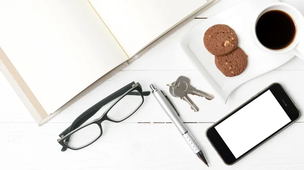 Чашка кави з печивом, телефоном, відкритим записником, ключем та окулярами — стокове фото