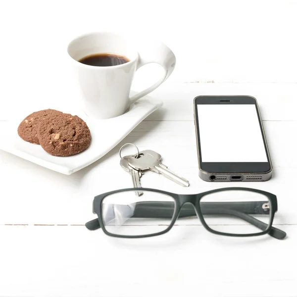 Taza de café con galletas, teléfono, anteojos y llave — Foto de Stock