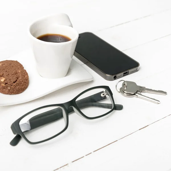 Taza de café con galletas, teléfono, anteojos y llave —  Fotos de Stock