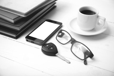 kahve fincanı ile telefon, araba anahtarı, gözlük ve kitap blac yığını