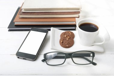 tanımlama bilgisi, telefon, kitap ve gözlük yığını ile kahve fincanı