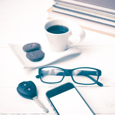 Kahve Kupası ile tanımlama bilgisi, telefon, araba anahtarı, gözlük ve kitap yığını