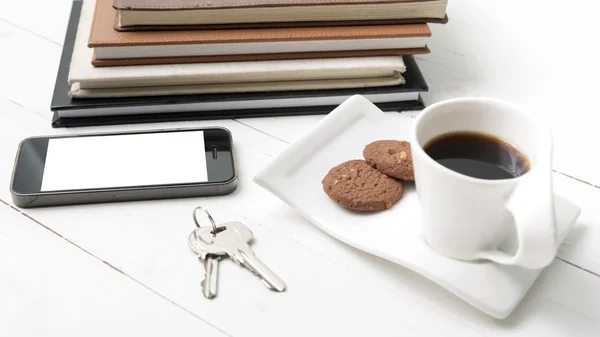 Tazza di caffè con biscotto, telefono, pila di libro e chiave — Foto Stock