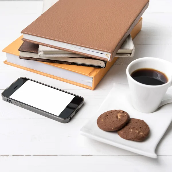 Koffie beker met cookie, telefoon en stack van boek — Stockfoto