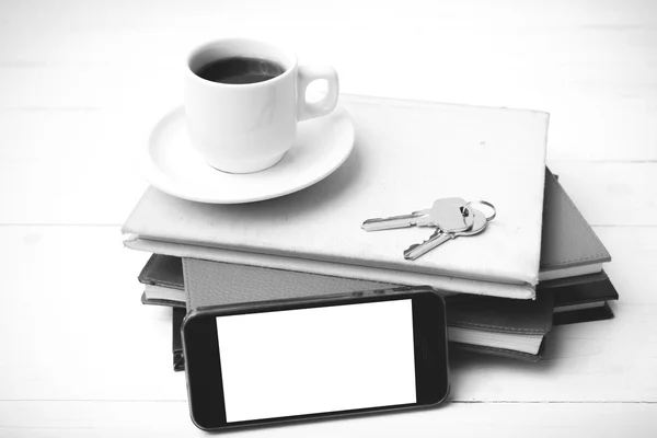 Xícara de café com telefone, chave e pilha de colo livro preto e branco — Fotografia de Stock