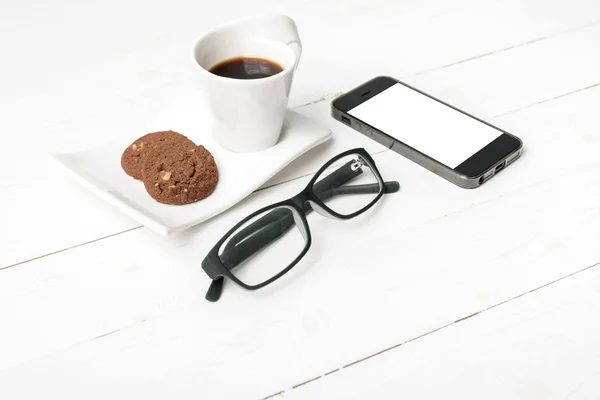 Xícara de café com biscoito, telefone e óculos — Fotografia de Stock