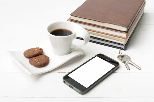 Tazza di caffè con biscotto, telefono, pila di libro e chiave — Foto Stock