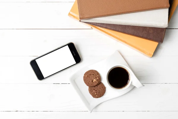 Taza de café con galletas, teléfono y pila de libros — Foto de Stock