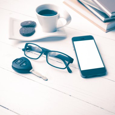 Kahve Kupası ile tanımlama bilgisi, telefon, araba anahtarı, gözlük ve kitap yığını