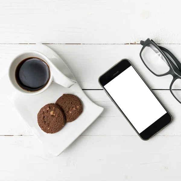 Xícara de café com biscoito, telefone e óculos — Fotografia de Stock