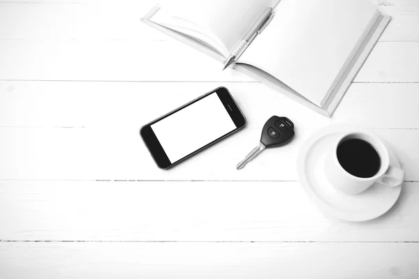 Xícara de café com telefone, chave do carro e aberto caderno preto e branco — Fotografia de Stock