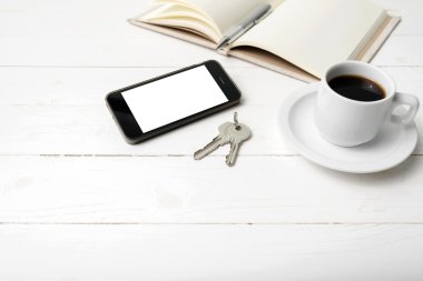 kahve fincanı ile telefon, anahtar ve açık defter