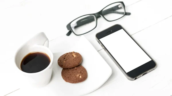 Tazza di caffè con biscotto, telefono e occhiali — Foto Stock