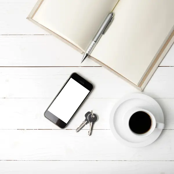 Xícara de café com telefone, chave e caderno aberto — Fotografia de Stock