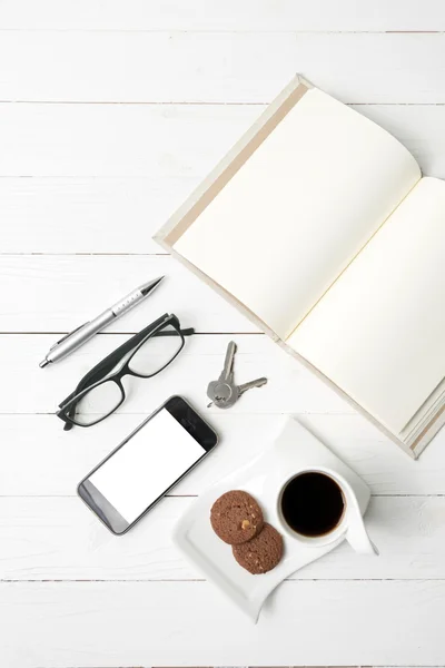 Xícara de café com biscoito, telefone, caderno aberto, chave e óculos — Fotografia de Stock