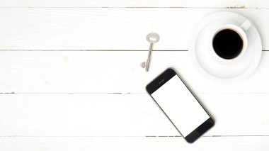 kahve fincanı ile telefon ve anahtar