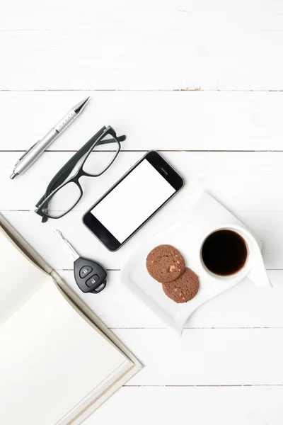 Tazza da caffè con biscotto, telefono, notebook aperto, chiave dell'auto e occhiale — Foto Stock