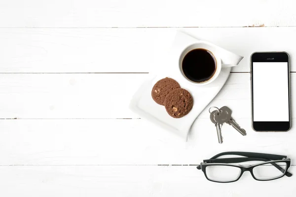 Xícara de café com biscoito, telefone, óculos e chave — Fotografia de Stock