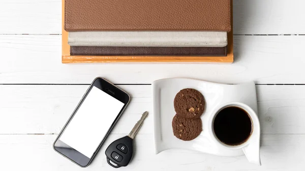 Чашка кави з печивом, телефоном, ключем автомобіля та стосом книги — стокове фото