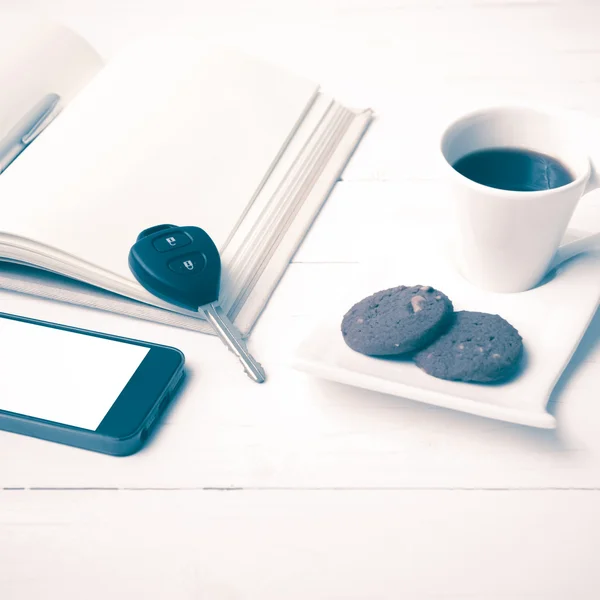 Чашка кави з печивом, телефоном, відкритим записником та автомобільним ключем старовинний с — стокове фото