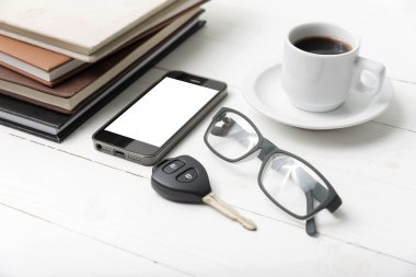 kahve fincanı ile telefon, araba anahtarı, gözlük ve kitap yığını