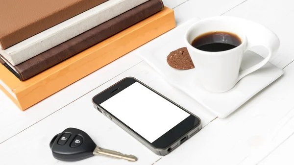 Чашка кави з печивом, телефоном, ключем автомобіля та стосом книги — стокове фото
