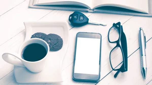 Чашка кави з печивом, телефоном, відкритим записником, ключем автомобіля та окулярами — стокове фото