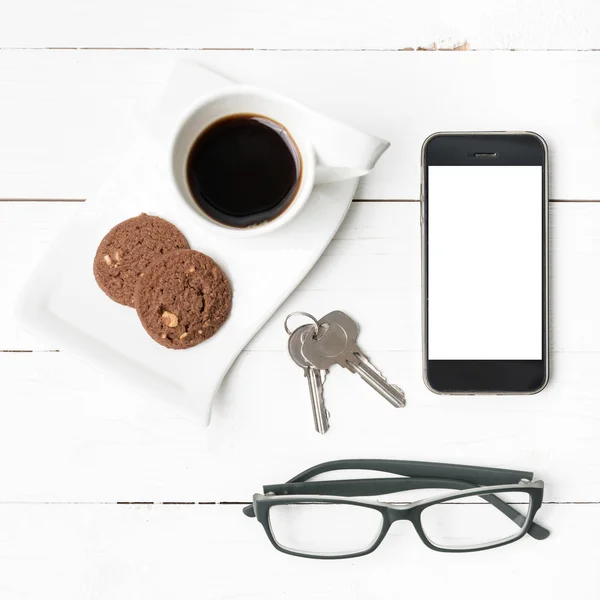 Xícara de café com biscoito, telefone, óculos e chave — Fotografia de Stock