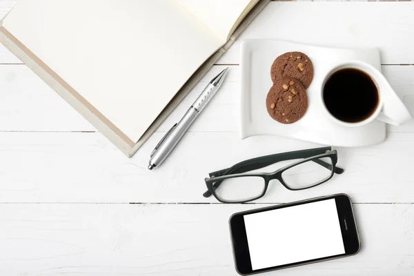 Xícara de café com biscoito, telefone, caderno e óculos — Fotografia de Stock