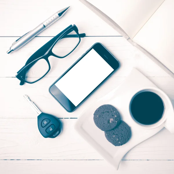 Tazza da caffè con biscotto, telefono, notebook aperto, chiave dell'auto e occhiale — Foto Stock