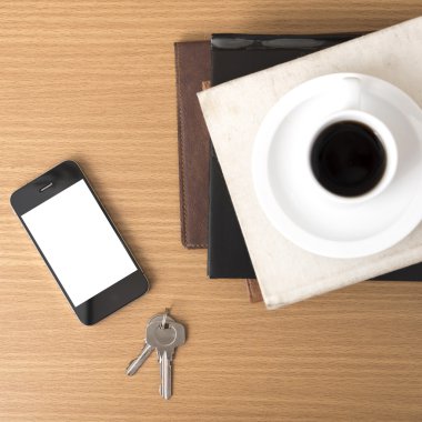 kahve fincanı ile telefon anahtar ve kitap yığını