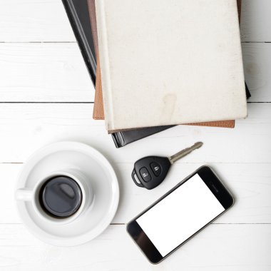 kahve fincanı ile telefon, araba anahtarı ve kitap yığını
