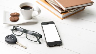 Kahve Kupası ile tanımlama bilgisi, telefon, araba anahtarı, gözlük ve kitap yığını