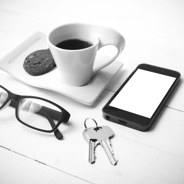 Taza de café con galletas, teléfono, anteojos y llave en blanco y negro — Foto de Stock