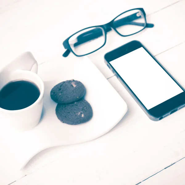 Чашка кофе с печеньем, телефон и очки винтажный стиль — стоковое фото